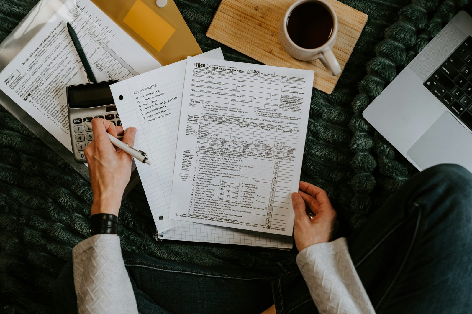 Practitioner reviewing tax workpapers with calculator and laptop